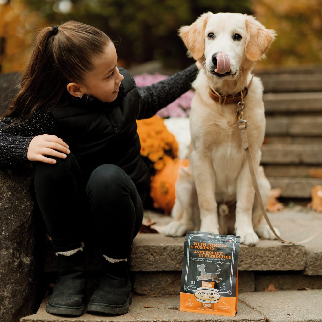 Jeune fille avec son chien et un sac de gâteries au poulet et à la citrouille.